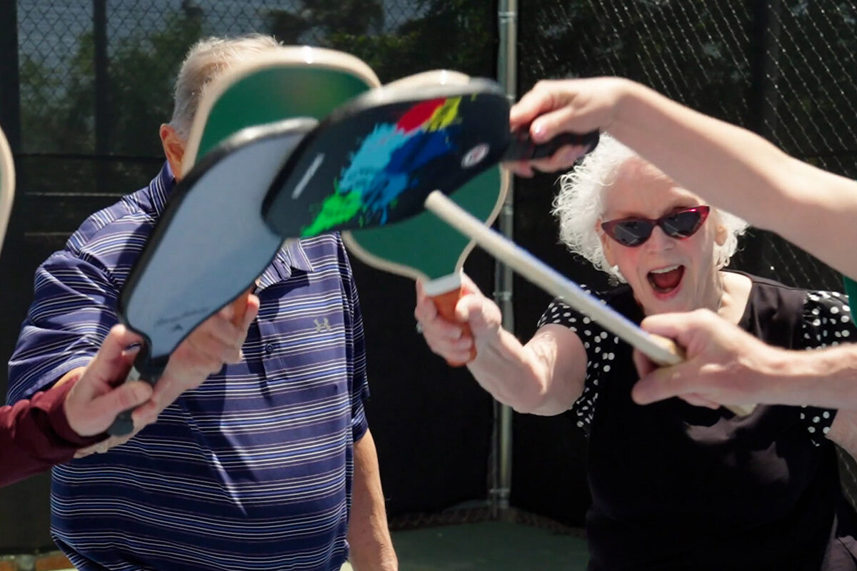 Older adults celebrating with pickleball paddles at luxury apartments in Las Vegas