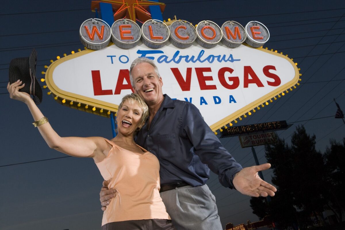 Happy couple celebrating at the Las Vegas sign, perfect for 55+ communities in Las Vegas at Lindell Living